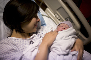 Mujer en la cama de un hospital con un recién nacido.