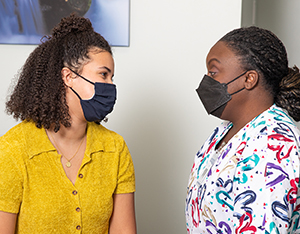 Health care provider consulting with patient, both wearing masks covering nose and mouth.